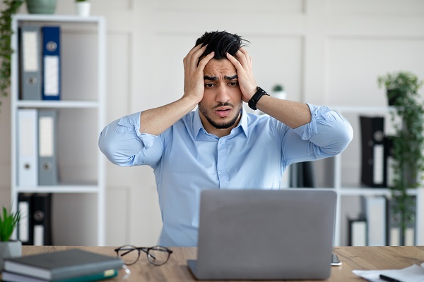 Man zit met handen in het haar achter computer